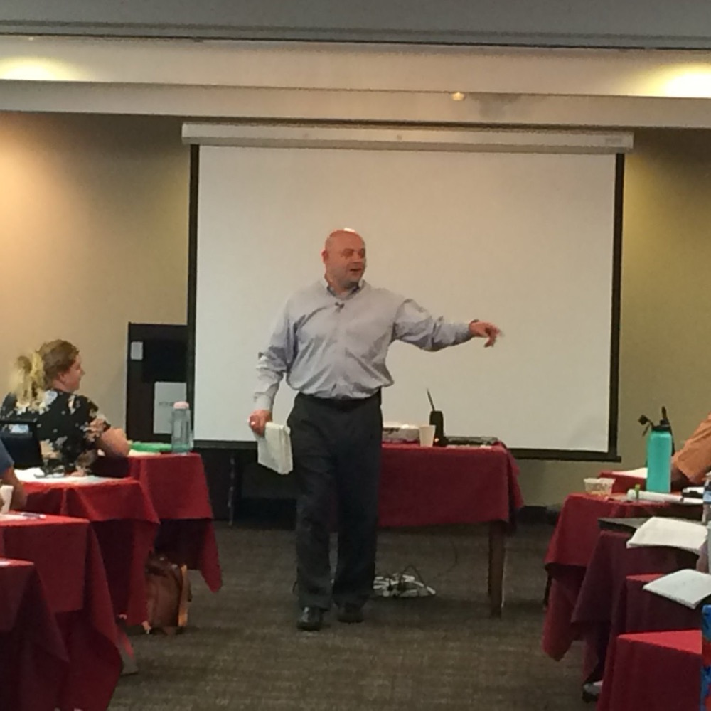 Kevin Macho speaking to a seminar audience, pointing to an attendee