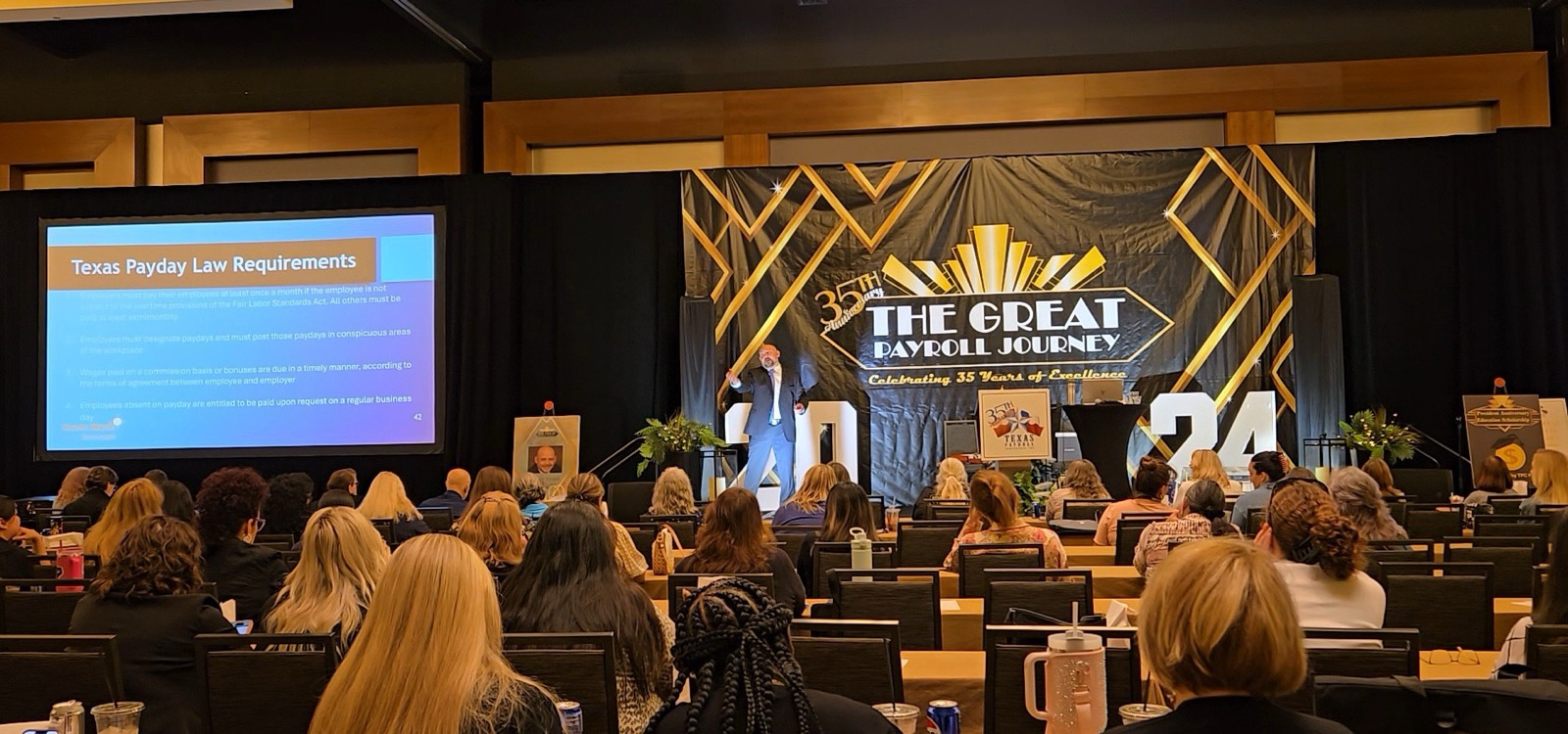 Kevin Macho speaking on stage to a packed conference ballroom
